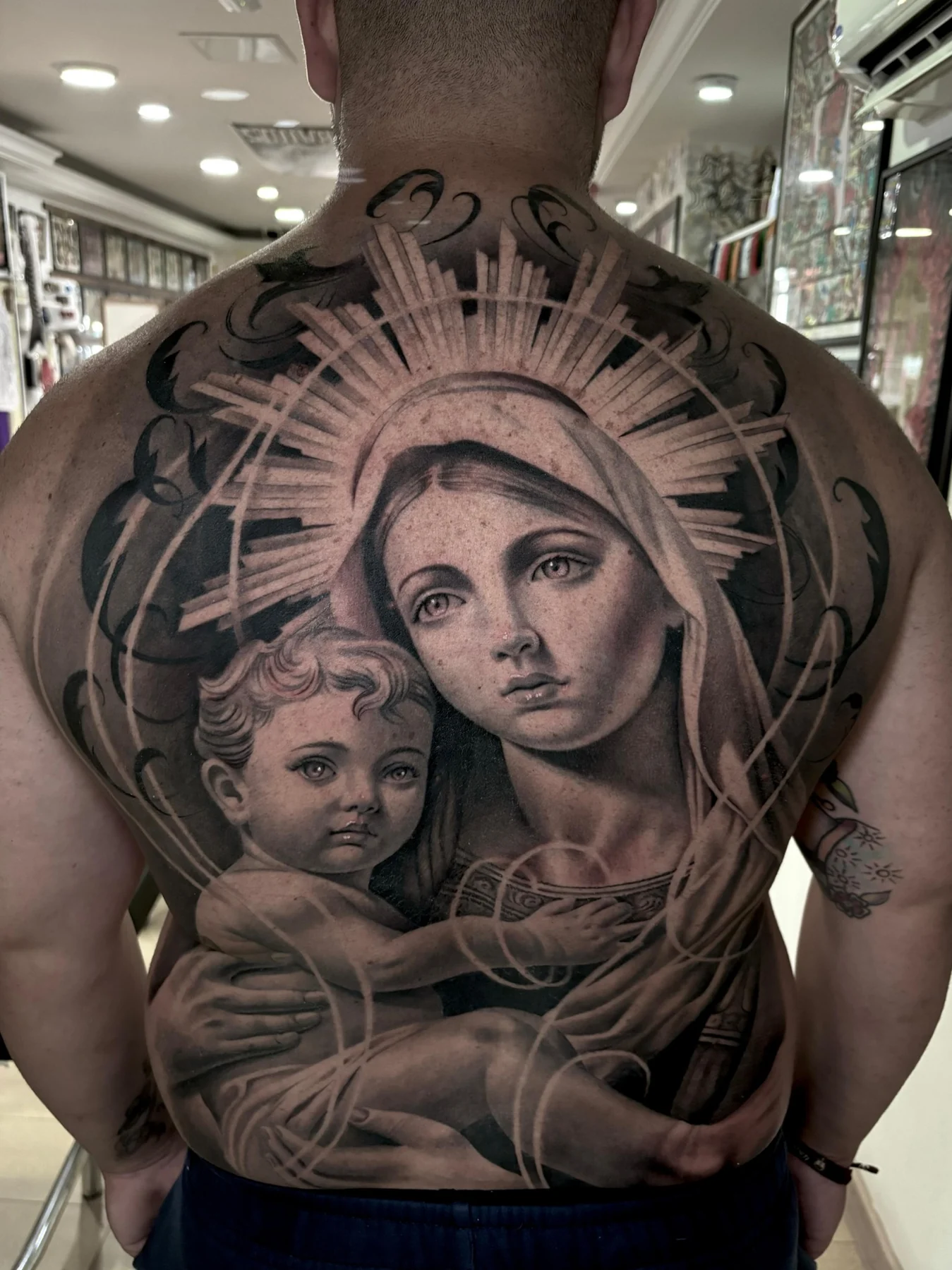 Tatuaje black and grey de la Virgen y el Niño realizado por Goodfellas Tattoo